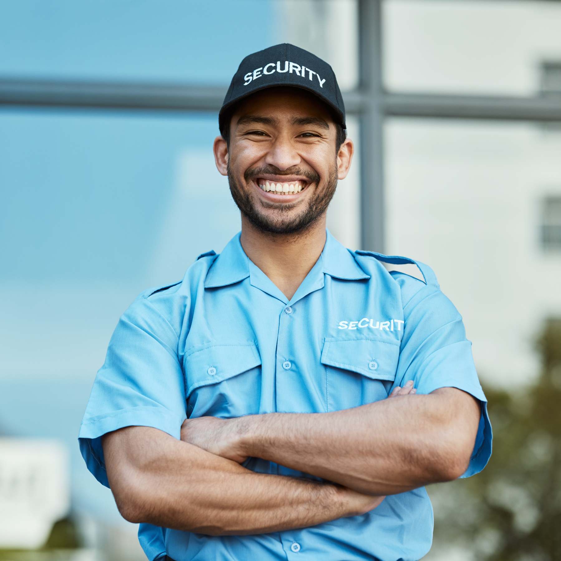 Agent de sécurité souriant devant un bâtiment.