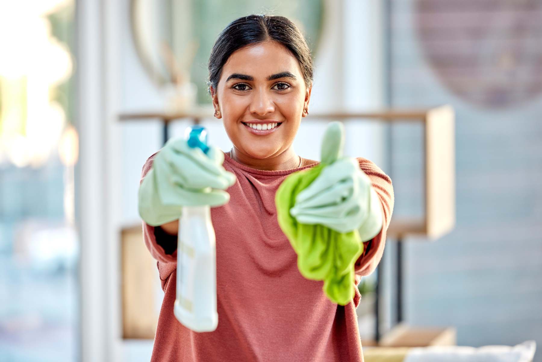 Femme tenant un produit de nettoyage et faisant un pouce levé, exprimant satisfaction et efficacité dans son ménage.